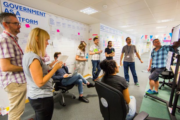 A group of GDS staff hold a discussion around the GaaP roadmap wall