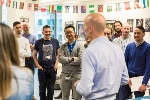 A group standup with several attendees laughing