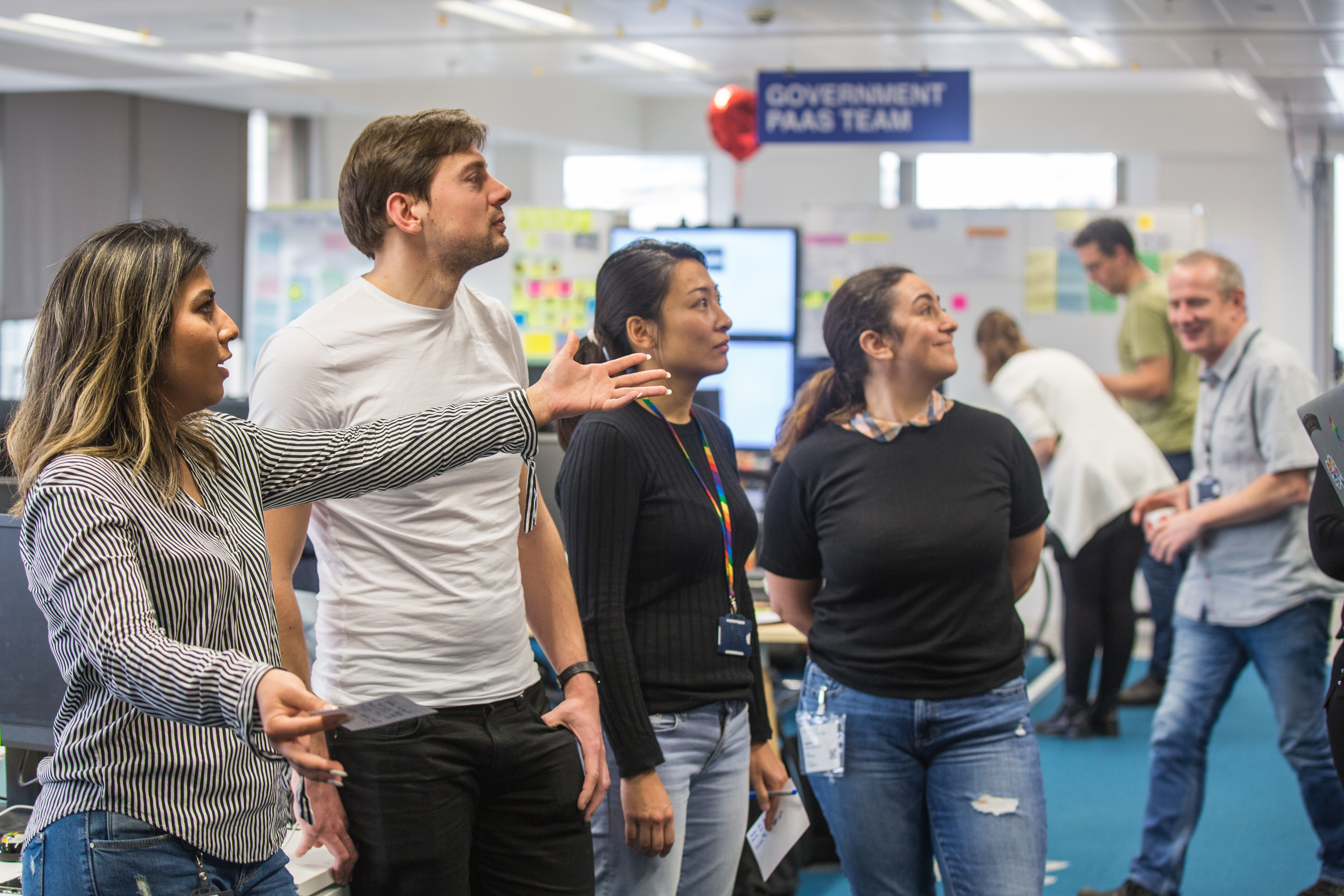 Members of the Gaap senior management team team talking in front of the team's agile wall.